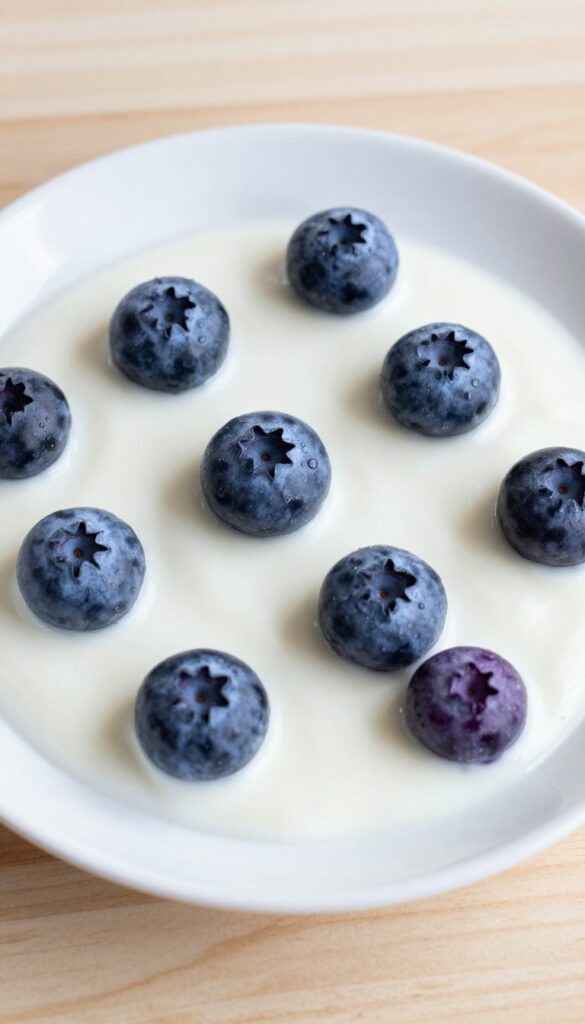 Frozen yogurt and blueberry drops for dogs, arranged on a plain plate in natural light, representing a homemade hypoallergenic treat recipe.