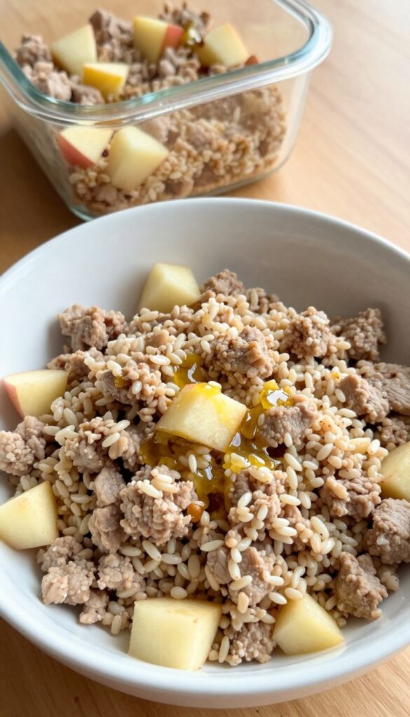 Homemade dog food recipe with ground pork, millet, and apple in a dog bowl, meal-prep style