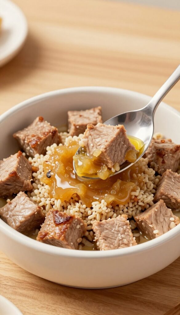 Homemade dog dinner bowl with lean pork tenderloin, applesauce, and quinoa, served in a dog bowl on a wooden table.