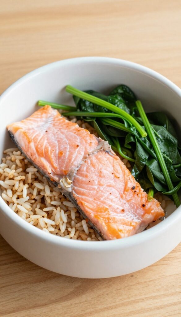 Homemade dog dinner bowl with salmon, spinach, and brown rice on a wooden surface.