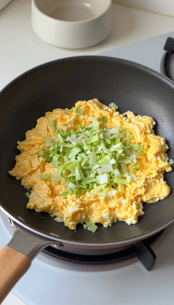 Scrambled eggs with finely chopped green cabbage cooking in a skillet for homemade dog food.